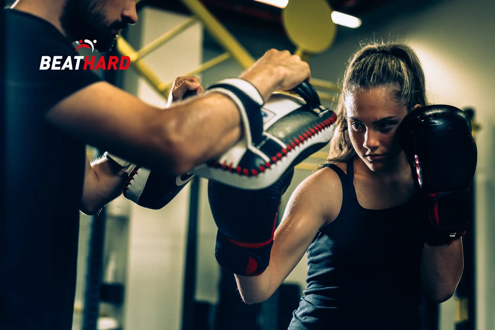 Entrenador con manoplas y boxeadora trabajando combinaciones
